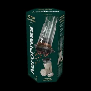 Zdjęcie opakowania zestawu AeroPress Go Plus w kolorze kremowym, prezentujące pełny system podróżny do parzenia kawy. Na pudełku widoczny jest AeroPress z uchodzącymi ziarnami kawy oraz ilustracja kremowego zestawu do parzenia kawy. Opakowanie zawiera informacje o technologii parzenia oraz kompletności zestawu.