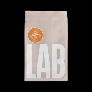 Opakowanie kawy Coffeelab Salvador Finca Las Brisas Carlos Pola w eleganckim, beżowym kolorze z dużym, białym napisem "LAB". Na opakowaniu znajduje się pomarańczowa etykieta z informacją o profilu smakowym kawy: żurawina, miód, kakao. Kawa dedykowana do espresso, pochodzi z Salwadoru z plantacji Finca Las Brisas. Produkt zapakowany w hermetyczne opakowanie z zamknięciem strunowym, które zapewnia świeżość ziaren.