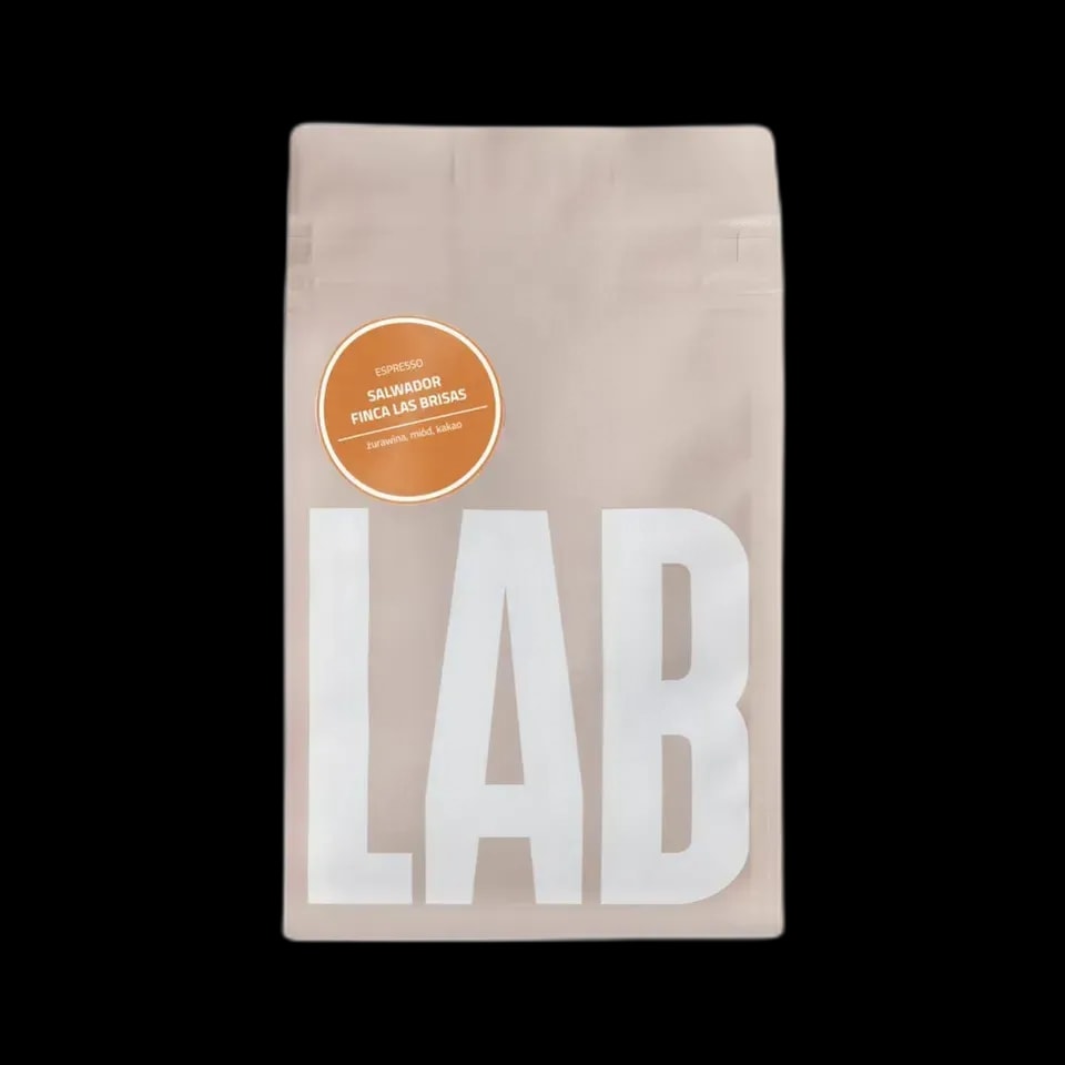 Opakowanie kawy Coffeelab Salvador Finca Las Brisas Carlos Pola w eleganckim, beżowym kolorze z dużym, białym napisem "LAB". Na opakowaniu znajduje się pomarańczowa etykieta z informacją o profilu smakowym kawy: żurawina, miód, kakao. Kawa dedykowana do espresso, pochodzi z Salwadoru z plantacji Finca Las Brisas. Produkt zapakowany w hermetyczne opakowanie z zamknięciem strunowym, które zapewnia świeżość ziaren.