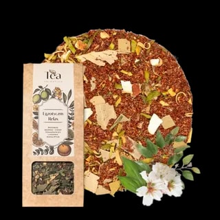 Herbata rooibos Egzotyczny Relax w ekologicznym opakowaniu, z dodatkiem skórki i kwiatu pomarańczy, limonki i eukaliptusa na tle białej miski wypełnionej herbatą. Obok leżą liście i kwiaty eukaliptusa.