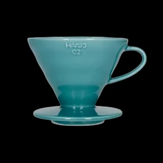 Stylowy ceramiczny dripper Hario V60-02 w turkusowym odcieniu, stworzony do precyzyjnego parzenia kawy metodą przelewową. Stożkowy kształt i spiralne żłobienia wewnętrzne zapewniają równomierną ekstrakcję, podkreślając głębię smaku świeżo mielonych ziaren.