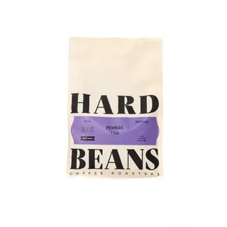 Na zdjęciu widoczna jest paczka kawy Hard Beans Pewniak Figa, opakowana w elegancki, minimalistyczny papier. Produkt ten to kawa jednoźródłowa, idealna do parzenia w metodzie filtrowej, charakteryzująca się wyjątkowym smakiem i aromatem.