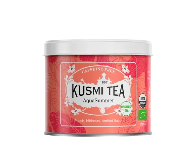 Metalowa puszka herbaty Kusmi Tea AquaSummer o pojemności 100 g w odcieniach koralowego z delikatnym roślinnym wzorem, zawierająca organiczną herbatę bezkofeinową o smaku brzoskwini, hibiskusa i moreli.
