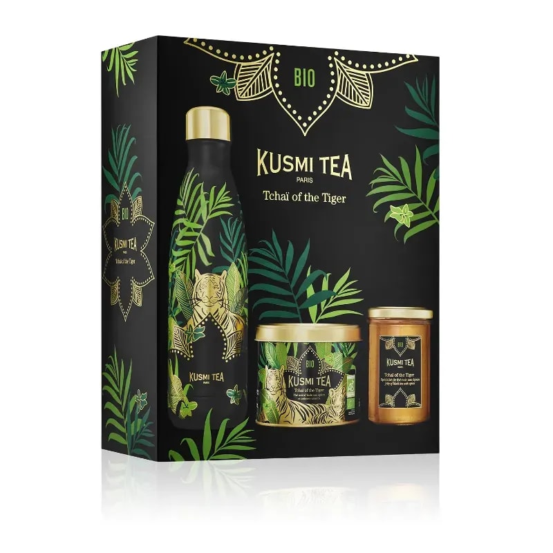 Opakowanie zestawu herbat Kusmi Tea Tchaï of the Tiger, ozdobione egzotycznym wzornictwem liści i tygrysa, idealne dla miłośników aromatycznych naparów. Doskonały wybór dla każdego, kto ceni sobie zdrowe, bio herbaty oraz eleganckie akcesoria do ich parzenia.