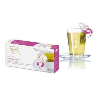 Opakowanie herbaty Ronnefeldt LeafCup Jasmine Gold obok szklanki z przygotowaną herbatą. Herbata Jasmine Gold to czarna herbata z mieszanką przypraw, oferowana w eleganckim pudełku z 15 torebkami herbaty, idealna do przygotowania aromatycznego napoju. Obok znajduje się przezroczysta szklanka z logo Ronnefeldt, ukazująca napój o bogatej, jasnej barwie.