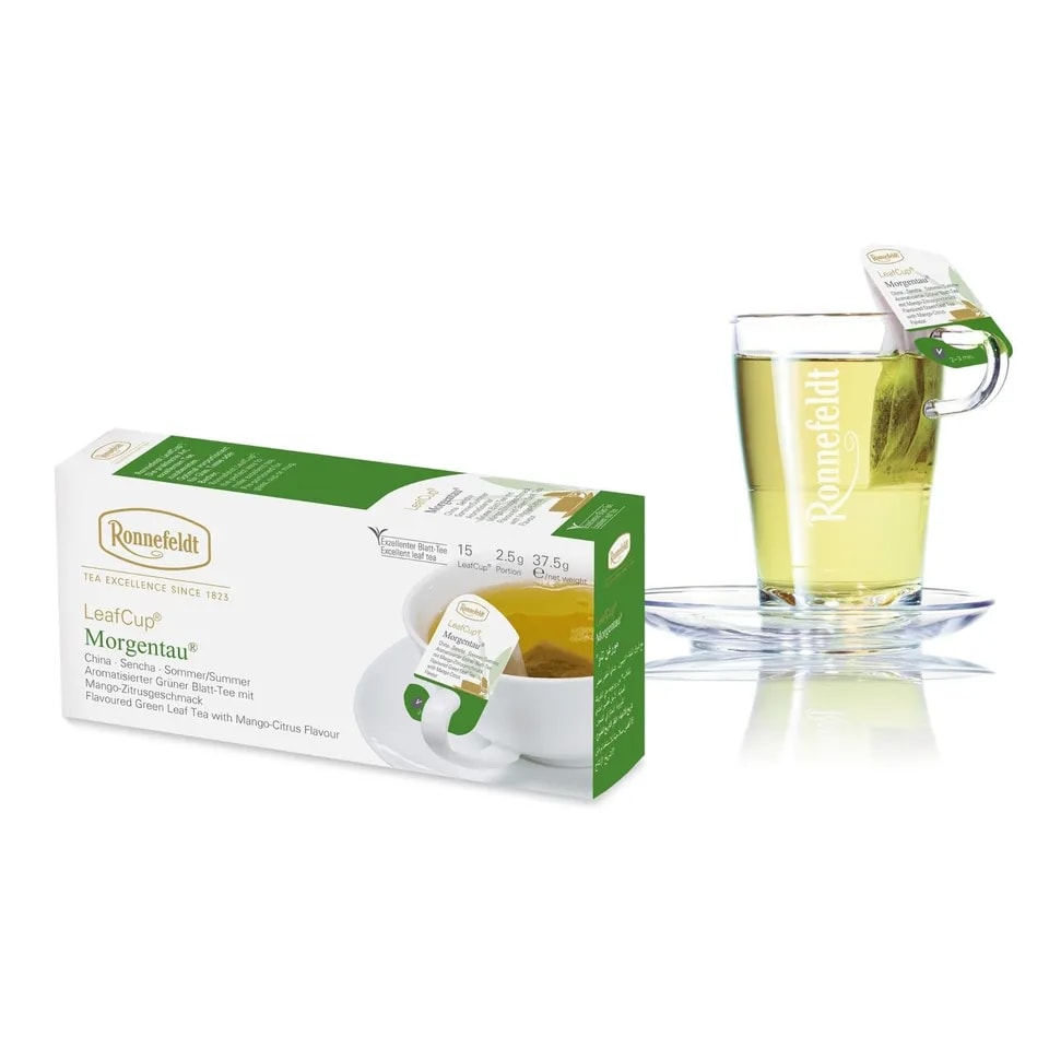 Opakowanie herbaty Ronnefeldt LeafCup Morgentau obok szklanki z przygotowaną herbatą. Herbata Morgentau to czarna herbata z mieszanką przypraw, oferowana w eleganckim pudełku z 15 torebkami herbaty, idealna do przygotowania aromatycznego napoju. Obok znajduje się przezroczysta szklanka z logo Ronnefeldt, ukazująca napój o bogatej, ciemnej barwie.