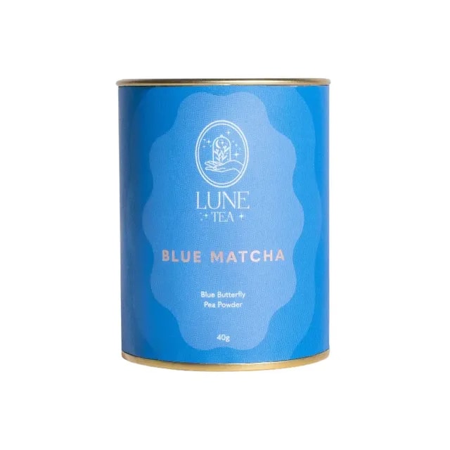 Opakowanie Lune Tea Blue Matcha z różowym akcentem i złotą obręczą, zawierające 40g proszku z kwiatu Klitorii Ternateńskiej. Idealne do przygotowania zdrowych napojów, zachwyca intensywnym kolorem i unikalnym smakiem, doskonałe dla miłośników herbat i innowacyjnych naparów.