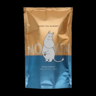 Opakowanie zielonej herbaty liściastej Moomin Green Tea Bilberry od Teministeriet o pojemności 100g. Torba w odcieniach złota i niebieskiego z wizerunkiem Muminka, minimalistycznym designem i napisem 'Moomin'. Herbata oferuje delikatne smaki jagody kamczackiej, tworząc wyjątkowe doświadczenie smakowe dla miłośników Muminków.