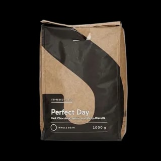 Opakowanie kawy ziarnistej Perfect Day Espresso Roast o pojemności 1 kg. Nowoczesny design z brązowo-czarną kolorystyką. Intensywna kawa o wyrazistych nutach gorzkiej czekolady, orzecha włoskiego i słodowych ciastek. Doskonała do przygotowania espresso, idealna dla miłośników bogatych smaków. Całe ziarna, przeznaczone do świeżego mielenia i parzenia w ekspresach ciśnieniowych lub alternatywnych metodach.