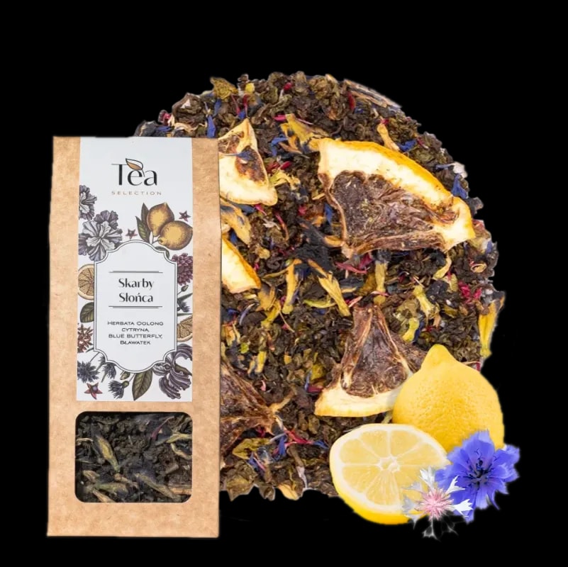 Opakowanie herbaty Skarby Słońca na białym tle, zawierającej mieszankę herbaty oolong, cytryny, blue butterfly oraz bławatera, obok talerz z suszonymi owocami i kwiatami, połowa cytryny, całe cytryny oraz niebieskie kwiaty chabra i białe kwiaty bławatera