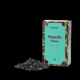 Chińska herbata oolong Teasome Magnolia z prowincji Fujian zapakowana jest w dekoracyjne pudełko z turkusowym frontem oraz widoczną porcją zwiniętych liści herbacianych. Aromatyzowana naturalnym kwiatem magnolii, tworzy delikatny, kwiatowy napar o subtelnym charakterze i eleganckim smaku.