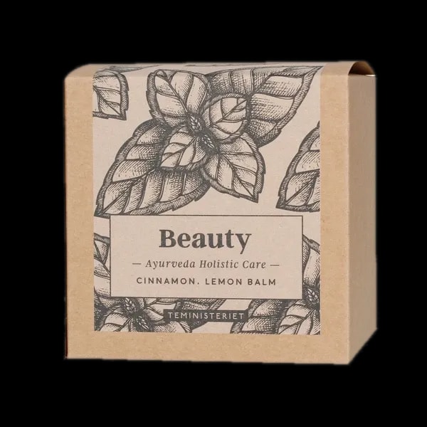 Opakowanie herbaty Teministeriet Ayurveda Beauty Organic o wadze 100g, na białym tle. Ziołowa mieszanka zawierająca cynamon i melisę, zapakowana w ekologiczne kartonowe opakowanie z minimalistycznym wzorem liści