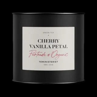 Puszka herbaty Teministeriet Cherry Vanilla Petal o wadze 100g, na białym tle. Organiczna zielona herbata o smaku wiśni i wanilii, certyfikowana Fairtrade, zapakowana w elegancką czarną puszkę