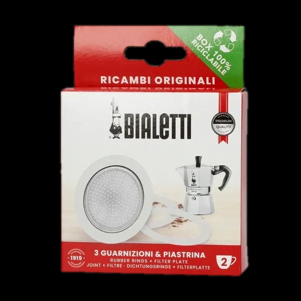 Opakowanie zawierające zestaw trzech uszczelek i sitko do kawiarek aluminiowych marki Bialetti, model 2 tz. Na zdjęciu widoczne jest pudełko z logiem Bialetti oraz rysunkiem kawiarki, a także informacją o zawartości - trzy gumowe uszczelki oraz metalowe sitko filtrujące. Zestaw przeznaczony do kawiarek aluminiowych, zapewnia dłuższą żywotność urządzenia oraz lepszą jakość parzenia kawy. Produkt jest zapakowany w ekologiczne opakowanie, w pełni nadające się do recyklingu.