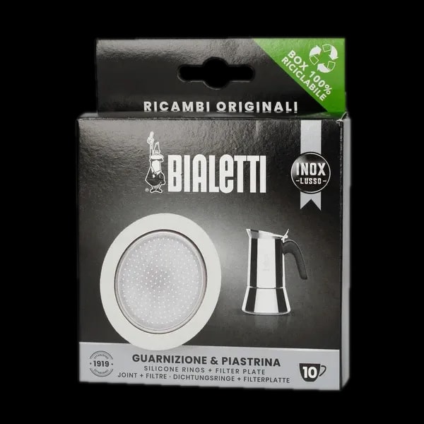 Opakowanie oryginalnego zestawu uszczelek i filtra do kawiarek stalowych Bialetti INOX LUSSO o rozmiarze 10 Tz. Produkt zawiera trzy silikonowe uszczelki oraz filtr z otworami, które są przeznaczone do kawiarek ze stali nierdzewnej Bialetti. Opakowanie w czarnym kolorze z białymi elementami, posiada logo Bialetti oraz zdjęcie kawiarki stalowej. Na górze opakowania widnieje informacja o 100% recyklingowalnym pudełku. Zestaw zapewnia wysoką jakość parzenia kawy i jest idealnym wyborem dla miłośników kawiarek Bialetti.