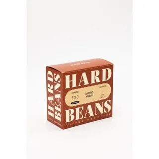 Na zdjęciu widoczna jest elegancka paczka kawy Hard Beans Rarytas Migdał, idealna do przygotowania wyjątkowego espresso. Połączenie intensywnego smaku z nutką migdałową sprawia, że jest to doskonały wybór dla wszystkich miłośników kawy poszukujących wyjątkowych doznań smakowych.