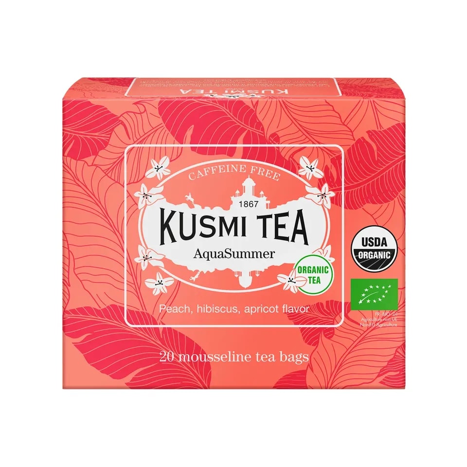 Pudełko herbaty Kusmi Tea AquaSummer w kolorze koralowym z liściastym wzorem, zawierające 20 saszetek herbaty owocowej z nutami brzoskwini, hibiskusa i moreli, oznaczone jako organiczne i bezkofeinowe.