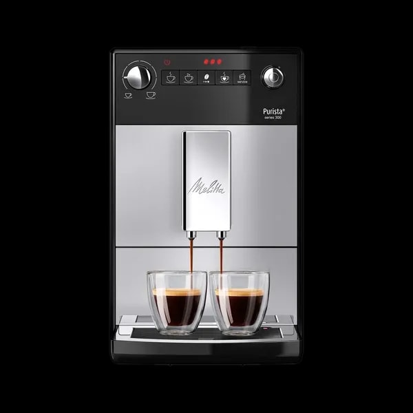 Ekspres ciśnieniowy Melitta Purista w kolorze srebrnym z czarnymi akcentami, widok z przodu. Urządzenie posiada dwa wylewki do kawy, umożliwiające przygotowanie dwóch filiżanek jednocześnie. Panel sterowania z przyciskami do wyboru różnych rodzajów kawy i przyciskami serwisowymi. Na dole znajduje się tacka ociekowa.