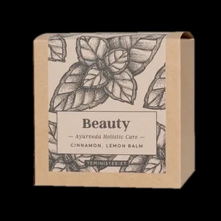 Opakowanie herbaty Teministeriet Ayurveda Beauty Organic o wadze 100g, na białym tle. Ziołowa mieszanka zawierająca cynamon i melisę, zapakowana w ekologiczne kartonowe opakowanie z minimalistycznym wzorem liści