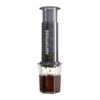 Zdjęcie czarnego zaparzacza AeroPress XL, umieszczonego na szklance, pokazującego proces parzenia kawy. Krople kawy delikatnie spadają do kubka, podkreślając wyjątkową metodę parzenia metodą AeroPress, z większym korpusem dla większej ilości kawy.