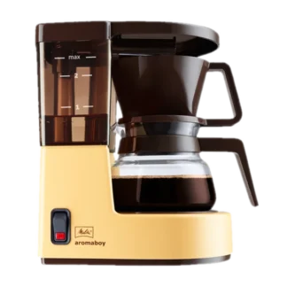 Ekspres przelewowy Melitta Aromaboy w kolorze beżowym, na białym tle. Kompaktowy design, idealny do parzenia 2 filiżanek kawy, wyposażony w szklany dzbanek, wskaźnik poziomu wody oraz funkcję automatycznego wyłączania