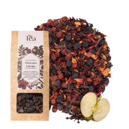 Opakowanie herbaty Owocowa Energia na białym tle, zawierającej mieszankę hibiskusa, jarzębiny, cynamonu, czarnego bzu, głogu, aronii, tarniny, goździków, jabłka, skórki dzikiej róży i jałowca, obok talerz z suszonymi owocami i przyprawami, pół jabłka, laska cynamonu oraz goździki