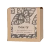 Opakowanie herbaty Teministeriet Ayurveda Beauty Organic o wadze 100g, na białym tle. Ziołowa mieszanka zawierająca cynamon i melisę, zapakowana w ekologiczne kartonowe opakowanie z minimalistycznym wzorem liści