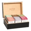 Skrzynka prezentowa VEERTEA Premium z drewna, wypełniona różnokolorowymi paczkami herbat, w tym smaki jak Citrus Tea, Earl Grey, oraz Cranberry & Raspberry, prezentowana na czarnym tle