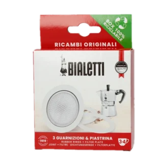 Zdjęcie zestawu uszczelek i sitek do kawiarek aluminiowych Bialetti 3-4 tz. Opakowanie zawiera trzy uszczelki gumowe i jedno sitko filtrujące, które są przedstawione na białym tle. Opakowanie w czerwono-białej kolorystyce z logotypem Bialetti oraz informacją o zawartości zestawu. Idealne do wymiany zużytych części w kawiarce, zapewniając długotrwałą jakość i doskonały smak kawy. Produkt ekologiczny, opakowanie w 100% nadające się do recyklingu.