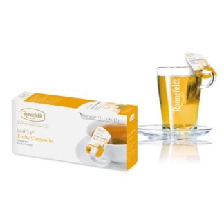 Opakowanie herbaty Ronnefeldt LeafCup Fruity Camomile, zawierające 15 saszetek herbaty rumiankowej, każda o wadze 1,4 g (21 g netto). Obok opakowania widoczna jest szklanka z gorącą herbatą z logo Ronnefeldt, z etykietą 'Fruity Camomile'. Opakowanie jest w tonacji bieli i żółci, z grafiką przedstawiającą kwiat rumianku.