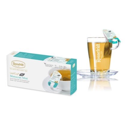 Opakowanie herbaty Ronnefeldt LeafCup Moroccan Mint, zawierające 15 saszetek zielonej herbaty z miętą pieprzową, każda o wadze 2,4 g (36 g netto). Obok opakowania widoczna jest szklanka z gorącą herbatą z logo Ronnefeldt, z etykietą 'Moroccan Mint'. Opakowanie jest w tonacji bieli i zieleni, z grafiką przedstawiającą miętę.