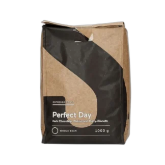 Opakowanie kawy ziarnistej Perfect Day Espresso Roast o pojemności 1 kg. Nowoczesny design z brązowo-czarną kolorystyką. Intensywna kawa o wyrazistych nutach gorzkiej czekolady, orzecha włoskiego i słodowych ciastek. Doskonała do przygotowania espresso, idealna dla miłośników bogatych smaków. Całe ziarna, przeznaczone do świeżego mielenia i parzenia w ekspresach ciśnieniowych lub alternatywnych metodach.