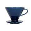 Elegancki ceramiczny dripper Hario V60-02 w głębokim kolorze indygo, idealny do precyzyjnego parzenia kawy metodą pour-over. Kultowy stożkowy kształt z wewnętrznymi żłobieniami zapewnia równomierną ekstrakcję, podkreślając pełnię smaku i aromatu ziaren.