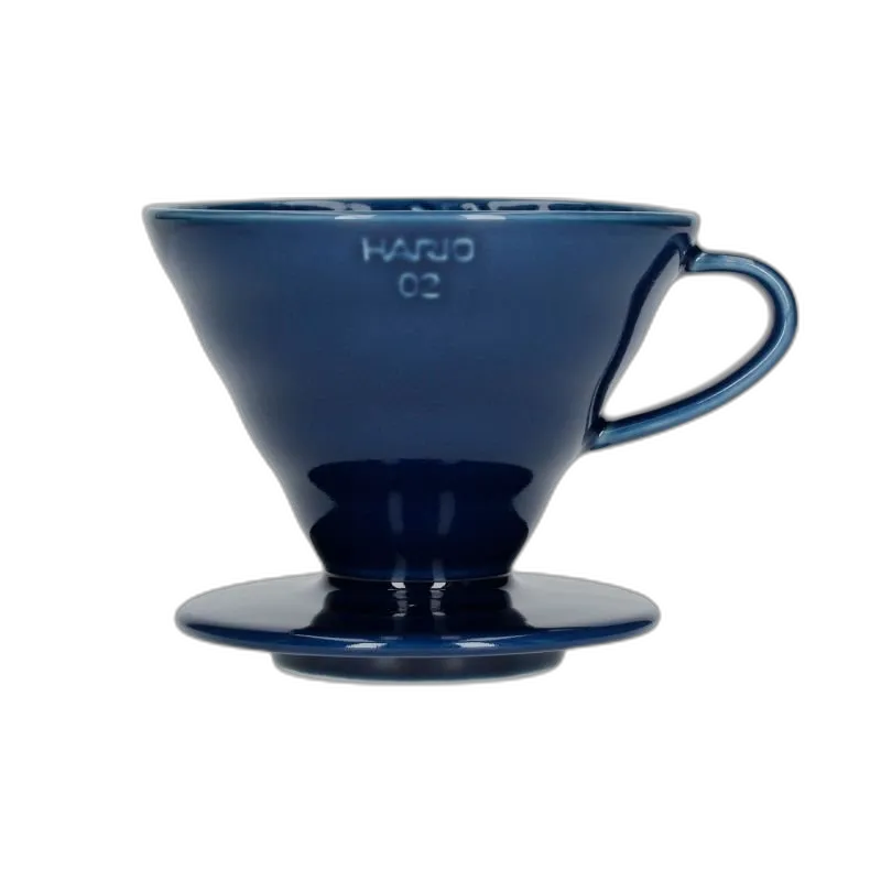 Elegancki ceramiczny dripper Hario V60-02 w głębokim kolorze indygo, idealny do precyzyjnego parzenia kawy metodą pour-over. Kultowy stożkowy kształt z wewnętrznymi żłobieniami zapewnia równomierną ekstrakcję, podkreślając pełnię smaku i aromatu ziaren.
