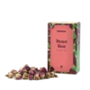Opakowanie herbaty kwiatowej Teasome Desert Rose z regionu Xinjiang w Chinach, zawierające 50 g aromatycznych, suszonych pąków róż o intensywnie różowym kolorze. Produkt zaprezentowany jest w dekoracyjnym pudełku z motywem roślinnym, obok którego ułożono naturalne kwiaty przeznaczone do parzenia.
