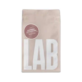 Opakowanie kawy Coffeelab Dominikana Finca La Colonia 250g – jasno wypalana kawa do metod przelewowych o nutach skóry, tytoniu i kakao, w minimalistycznym beżowym opakowaniu z białym logo LAB.
