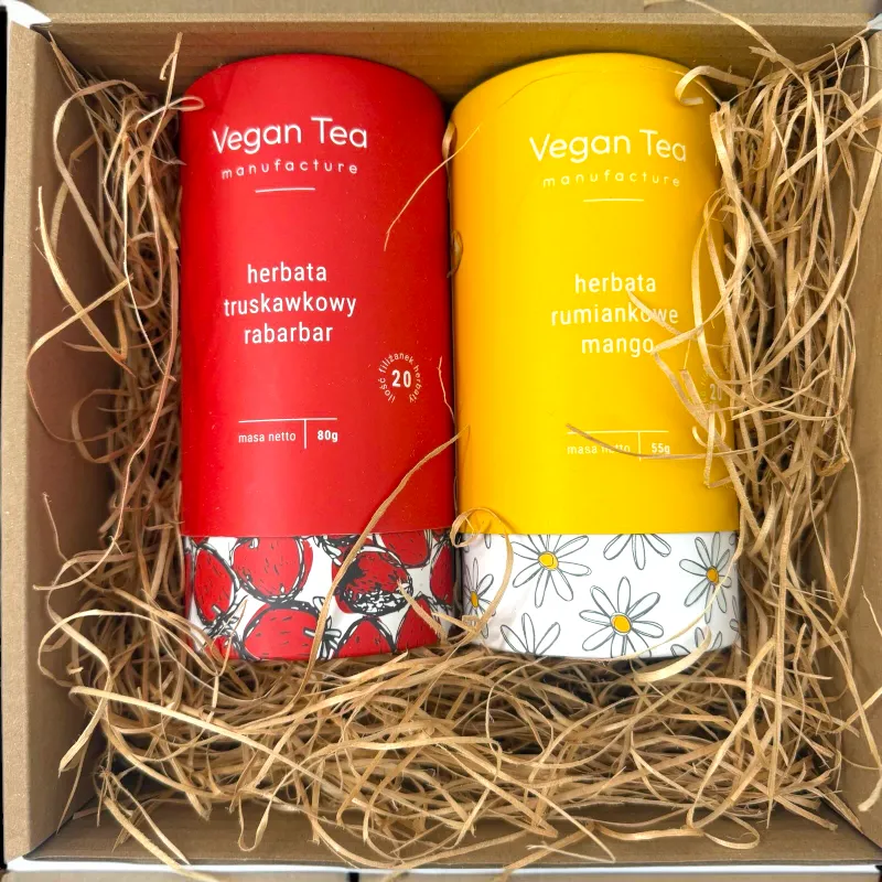 Zestaw dwóch herbat Vegan Tea w ozdobnych tubach – truskawkowy rabarbar (80 g) i rumiankowe mango (55 g) – zapakowany w pudełko z naturalną wyściółką.