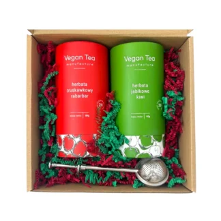 Zestaw prezentowy Vegan Tea z dwiema herbatami – truskawkowy rabarbar i jabłkowe kiwi – oraz metalowym zaparzaczem, zapakowany w ozdobne pudełko z czerwoną i zieloną wyściółką.