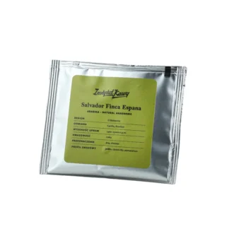 Srebrne opakowanie kawy Salvador Finca Espana od Instytutu Kawy w formie drip bag. Zielona etykieta z informacjami o profilu smakowym (jabłko, ciasteczko, pomarańcza), regionie El Balsamos, odmianie Castillo i Bourbon oraz wysokości upraw 1400–1500 m n.p.m.