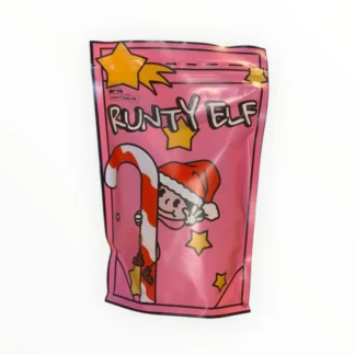 Na zdjęciu znajduje się kolorowa paczka kawy RUNTY ELF, ozdobiona wesołym rysunkiem elfa trzymającego cukrową laskę. Produkt idealny na świąteczne chwile, oferujący wyjątkowy smak i aromat, który umili każdą filiżankę kawy.
