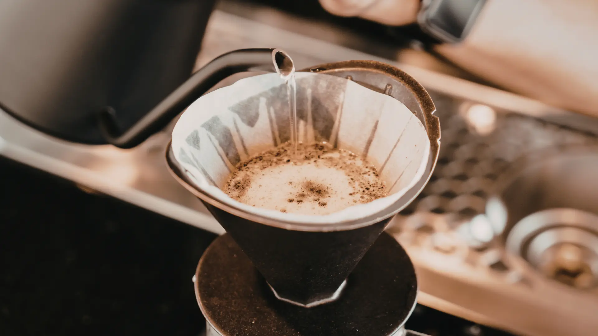Drip V60 podczas parzenia kawy metodą przelewową – gorąca woda wlewana z precyzyjnego czajnika do papierowego filtra z mieloną kawą, zbliżenie na proces ekstrakcji aromatycznego naparu.
