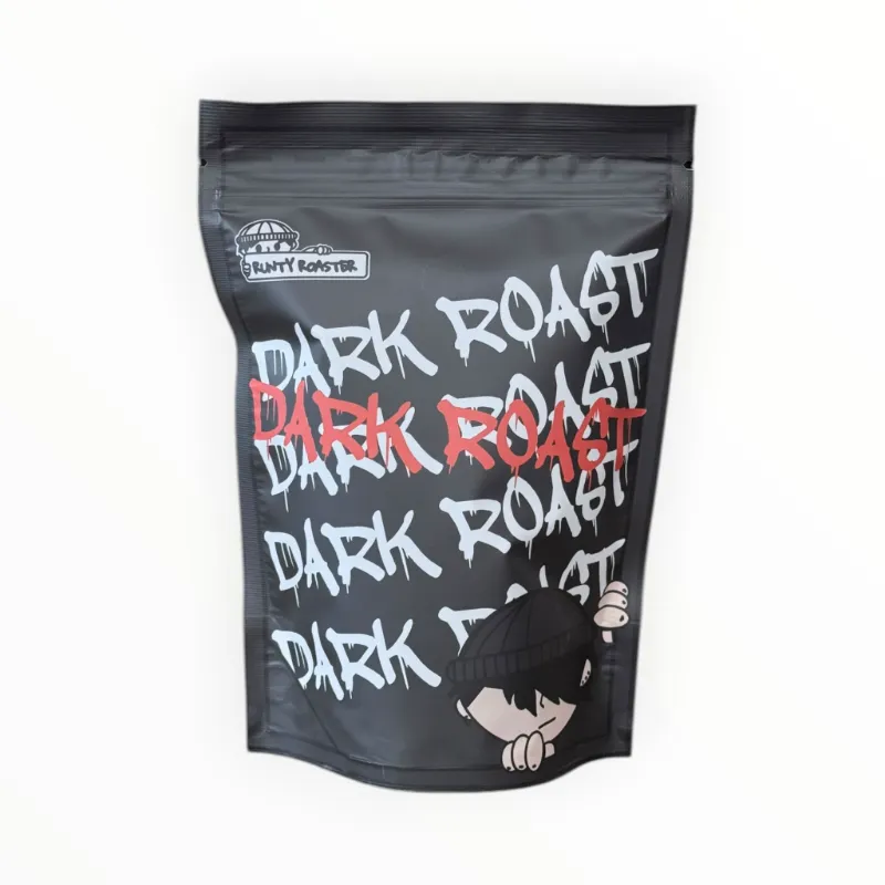 Opakowanie kawy Dark Roast prezentuje się na tle minimalistycznym, z wyraźnymi napisami w kontrastujących kolorach. Idealna dla miłośników intensywnych smaków, ta kawa świetnie sprawdzi się w każdym domowym kąciku kawowym.